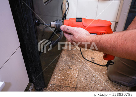 Man drilling hole in kitchen oven door 138820785