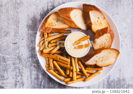 Close up of egg sauce in a bowl, breadsticks and bread on a plate on the table top view Close up of egg sauce in a bowl, breadsticks and bread on a plate on the table top view 138821042