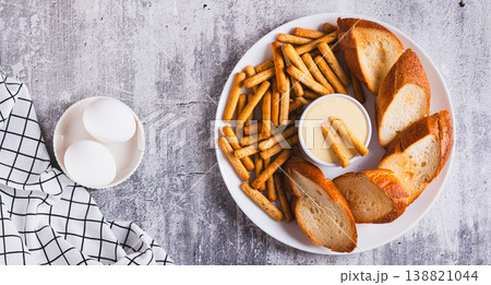 Hollandaise sauce with breadsticks and toast on a plate on the table top view web banner Hollandaise sauce with breadsticks and toast on a plate on the table top view web banner 138821044