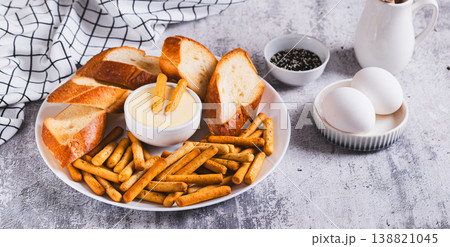 Egg sauce in a bowl, breadsticks and bread on a plate on the table web banner 138821045
