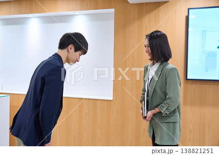 オフィスで笑顔で挨拶とお辞儀を交わす男女のビジネスパーソン 138821251