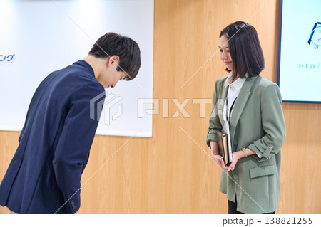 オフィスで笑顔で挨拶とお辞儀を交わす男女のビジネスパーソン オフィスで笑顔で挨拶とお辞儀を交わす男女のビジネスパーソン 138821255