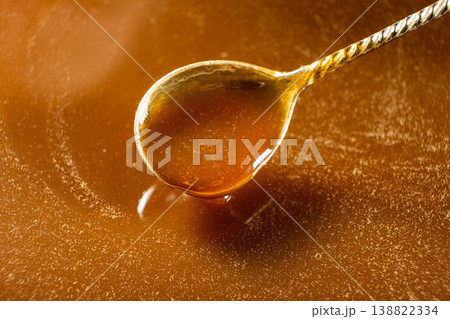 Liquid caramel sauce dripping from silver spoon. 138822334