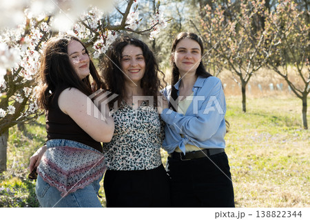 Beautiful portrait of three sisters embracing in a spring blooming garden. Beautiful portrait of three sisters embracing in a spring blooming garden. 138822344