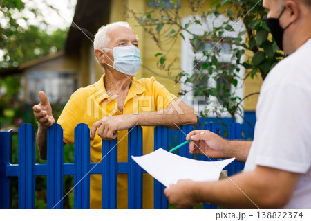 Old man in mask talking with employer of public utilities outdoors 138822374
