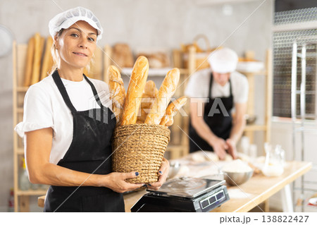 Elderly woman with basket of baguettes in bakery Elderly woman with basket of baguettes in bakery 138822427