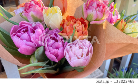 Beautiful bouquets of colorful double peony tulips wrapped in craft paper in soft morning sunlight Beautiful bouquets of colorful double peony tulips wrapped in craft paper in soft morning sunlight 138822469