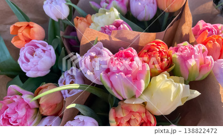 Beautiful bouquets of colorful double peony tulips wrapped in craft paper in soft morning sunlight 138822472