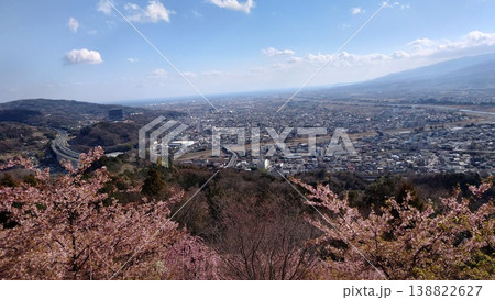 桜の花道へと続く道路と家並み、山並みが彩る春の風景 138822627