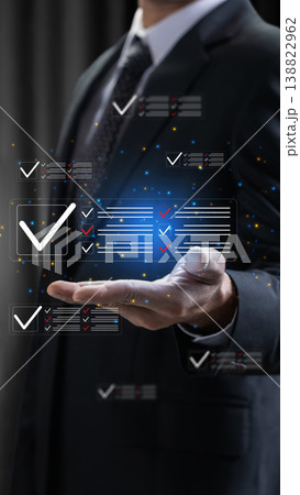 A professional businessman interacts with a futuristic digital interface showing completed checklists, symbolizing task management, quality control, and efficient business workflow 138822962