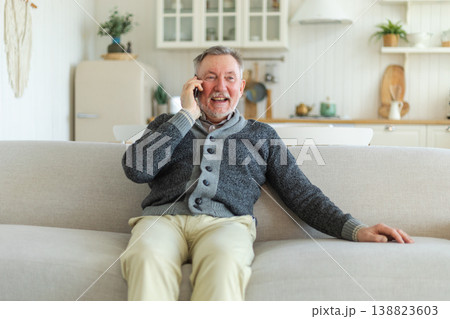 Happy middle aged senior man talking on smartphone with family friends. Older mature grandfather with cell phone talking with grown up children, resting at home. Older generation modern tech usage 138823603