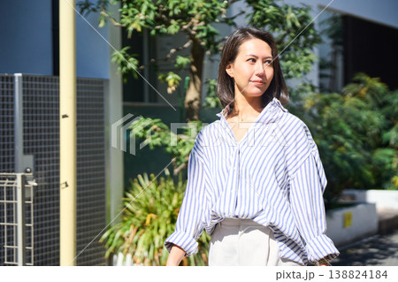 買い出しの帰り道、スマホを片手に笑顔で休日の散歩を楽しむ日本人女性。 138824184