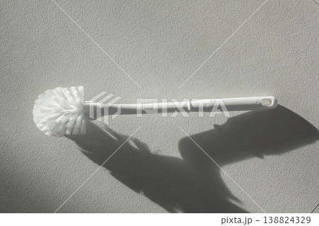 A white toilet brush is lying on the floor. A white toilet brush is lying on the floor. 138824329
