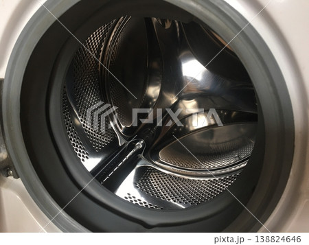 Washing machine showing spinning drum with metal interior and rubber seal during laundry cycle in a home setting Washing machine showing spinning drum with metal interior and rubber seal during laundry cycle in a home setting 138824646
