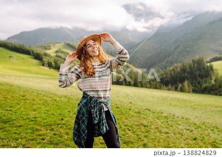 Cheerful happy woman smiles, laughs, emotional in nature, against backdrop of mountain landscapes. 138824829