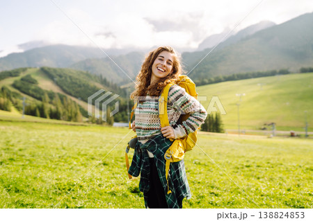 Female tourist with yellow backpack on top of mountain enjoying view of valley. Hiking concept. 138824853