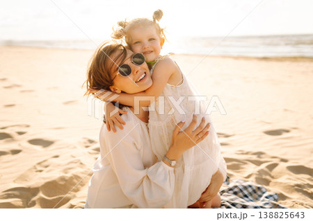 Portrait of mother and daughter enjoying a beach stroll at sunset. Moment of love and playfulness Portrait of mother and daughter enjoying a beach stroll at sunset. Moment of love and playfulness 138825643