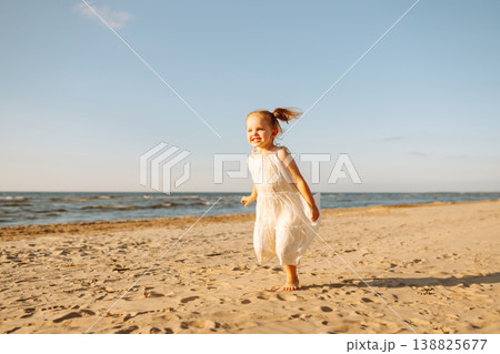 Young girl joyfully plays on the sandy beach during sunset, enjoying a carefree moment by the ocean Young girl joyfully plays on the sandy beach during sunset, enjoying a carefree moment by the ocean 138825677