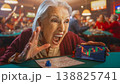 A grandmother is in the center of a busy bingo hall, shouting with excitement. She holds a bingo card and cheers loudly. Others are playing in the background, enjoying the moment. 138825741