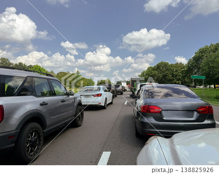 Multiple lanes of vehicles and trucks are stopped in slow traffic on a busy highway under a cloudy sky. The scene represents transportation congestion, travel delay, and everyday road movement in Multiple lanes of vehicles and trucks are stopped in slow traffic on a busy highway under a cloudy sky. The scene represents transportation congestion, travel delay, and everyday road movement in 138825926