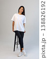 Casual Asian content creator dressed in white shirt relaxing on stool for social media visuals 138826192