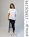Casual Asian content creator dressed in white shirt relaxing on stool for social media visuals 138826198
