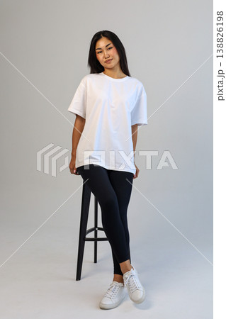 Casual Asian content creator dressed in white shirt relaxing on stool for social media visuals Casual Asian content creator dressed in white shirt relaxing on stool for social media visuals 138826198