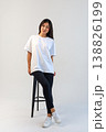 Casual Asian content creator dressed in white shirt relaxing on stool for social media visuals 138826199