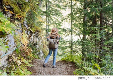 Woman with backpack hiking outdoors in the Forest. Trekking in the Pine Woods. Hiking lifestyle Woman with backpack hiking outdoors in the Forest. Trekking in the Pine Woods. Hiking lifestyle 138826227