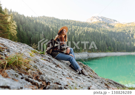 Young woman traveler enjoys fresh air and a beautiful view of the lake and mountains. Active life 138826289