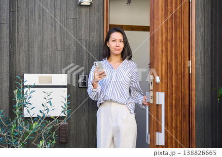 スマホを手に一軒家の玄関から外出する日本人女性 スマホを手に一軒家の玄関から外出する日本人女性 138826665