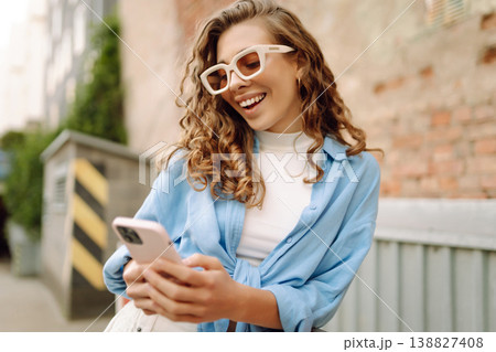 Portrait happy woman walking with phone in city. Online Communication with friend. Lifestyle concept Portrait happy woman walking with phone in city. Online Communication with friend. Lifestyle concept 138827408