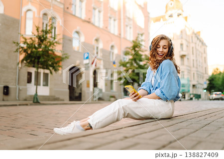 Happy relaxed woman in wireless headphones choosing, listening favorite music in urban city street. Happy relaxed woman in wireless headphones choosing, listening favorite music in urban city street. 138827409