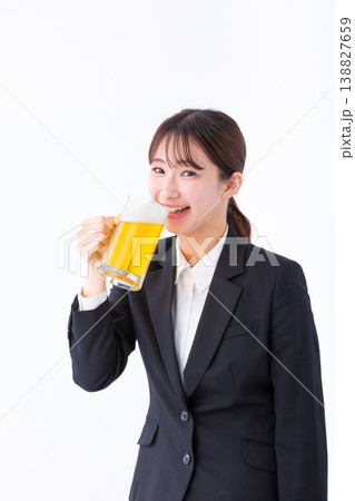笑顔でビールを飲むスーツ姿の若い女性 笑顔でビールを飲むスーツ姿の若い女性 138827659