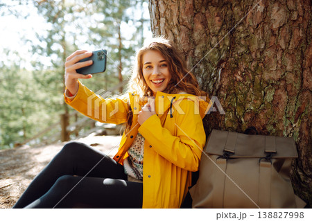 Happy woman with phone in hands taking selfie in forest. Young tourist enjoying spring day near lake Happy woman with phone in hands taking selfie in forest. Young tourist enjoying spring day near lake 138827998