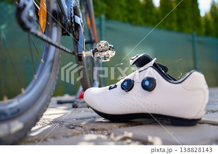 White cycling shoe beside a clipless pedal on a road bike White cycling shoe beside a clipless pedal on a road bike 138828143