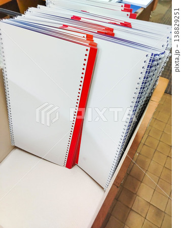 Stack of blank spiral-bound notebooks with red and blue covers arranged neatly on a wooden surface in an office or school environment Stack of blank spiral-bound notebooks with red and blue covers arranged neatly on a wooden surface in an office or school environment 138829251