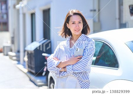 晴れた屋外でスマホを持ち笑顔を見せる日本人女性のポートレート 晴れた屋外でスマホを持ち笑顔を見せる日本人女性のポートレート 138829399