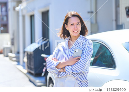 晴れた屋外でスマホを持ち笑顔を見せる日本人女性のポートレート 晴れた屋外でスマホを持ち笑顔を見せる日本人女性のポートレート 138829400
