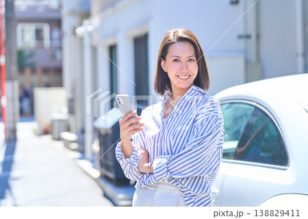 屋外でスマホを手に持ち笑顔を向ける日本人女性のポートレート 屋外でスマホを手に持ち笑顔を向ける日本人女性のポートレート 138829411