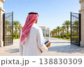 Arab male student walking toward university campus holding books in sunny day 138830309