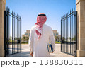 Middle Eastern man entering modern campus gate holding books from behind 138830311