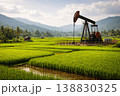 Oil pump jack working in green agricultural field with mountains in background 138830325