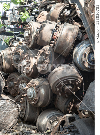 a disorganized pile of industrial scrap, specifically heavy-duty drum brake assemblies. These weathered components, likely salvaged from large trucks, feature prominent wheel studs extending from 138830783