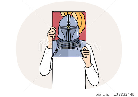 Book with knight on cover in hands of man covering face, reading literature about medieval soldiers Book with knight on cover in hands of man covering face, reading literature about medieval soldiers 138832449
