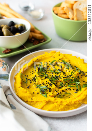 Gather around a colorful charcuterie board featuring turmeric hummus, cheese, nuts, and olives. This delightful spread invites friends to share tasty bites and enjoy each other company 138832811