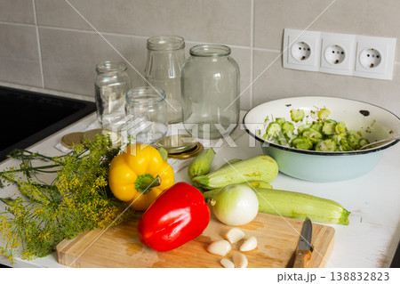 Cucumbers, peppers, and zucchini are being prepared and placed in jars for canning. Fresh ingredients are cut and organized on a clean kitchen counter for preserving Cucumbers, peppers, and zucchini are being prepared and placed in jars for canning. Fresh ingredients are cut and organized on a clean kitchen counter for preserving 138832823