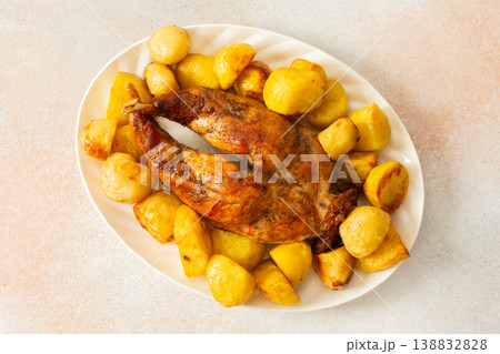 A beautifully presented dish features a whole baked rabbit surrounded by tender, golden-roasted potatoes. This comforting meal is perfect for family gatherings or special occasions. A beautifully presented dish features a whole baked rabbit surrounded by tender, golden-roasted potatoes. This comforting meal is perfect for family gatherings or special occasions. 138832828