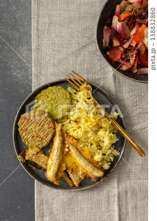 A wholesome breakfast featuring turmeric rice with baked ocean fish, complemented by broccoli pancakes and roasted vegetables, offering a nutritious and satisfying meal 138832860