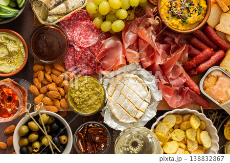 Taste a variety of flavors with this charcuterie board filled with cheese, sausages, hummus, nuts, and fresh sandwiches, perfect for any gathering 138832867
